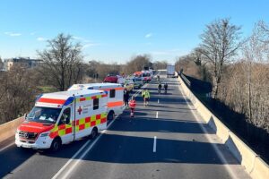 Rettungswagen und Hubschrauber an Unfallstelle mit mehreren Fahrzeugen und Verletzten.