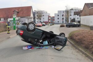 Ein umgedrehtes Auto auf der Straße nach einem Unfall mit einer verletzten Fahrerin.