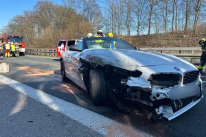 Drei beschädigte Fahrzeuge, Feuerwehr im Einsatz, gesperrte Autobahn, Verletzte, Rettungsmaßnahmen.