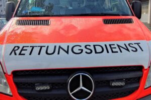 Rettungswagen am Unfallort, verletzter Motorrollerfahrer wird versorgt, Unfallstelle auf der Straße.