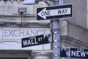 Finanzcharts und Börsenkurse mit dem Wall Street-Symbol und abnehmenden Indizes auf einem Bildschirm.