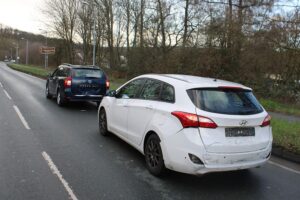 Unfallstelle mit drei beschädigten Fahrzeugen, Polizei vor Ort, Rettungskräfte leisten Erste Hilfe.