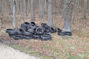 Haufen Altreifen illegal entsorgt an Parkplätzen, symbolisiert Umweltverschmutzung und Schäden für Natur.