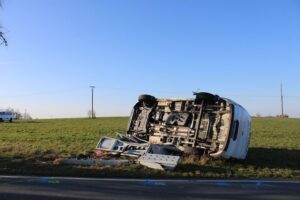 Umgekippter Van nach Unfall, verletzter Fahrer, Polizei und Rettungswagen im Einsatz.