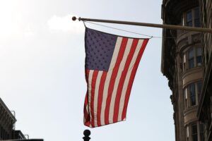 US-Flagge vor militärischem Hintergrund, symbolisiert Verlust und Trauer nach Flugzeugabsturz im Irak.