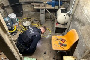 Zollbeamte durchsuchen Keller, Sicherstellung von Beweisen und Waffen während Ermittlungen gegen Schwarzarbeit.