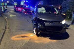 Zwei beschädigte Pkw an Kreuzung nach Verkehrsunfall, Feuerwehr sichert die Unfallstelle.