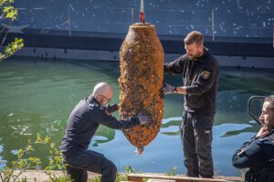 Kampfmittelräumdienst verlädt entschärfte Fliegerbombe vom Baggerschiff auf Land in Koblenz.