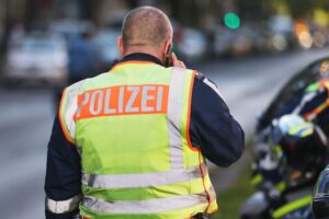 Gruppen von Jugendlichen in der Stadt, Polizei im Hintergrund, Szene einer Schlägerei.