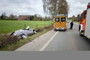 Feuerwehr und Polizei sichern Unfallstelle: Autofahrer im Graben, Einsatzkräfte retten Verletzten.