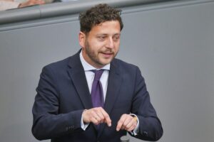 Felix Banaszak kritisiert Merz' Krisenmanagement während einer Pressekonferenz in Berlin.