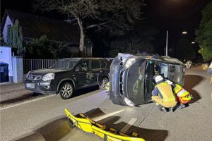 Ein umgekipptes Auto auf der Seite, Rettungskräfte befreien den eingeklemmten Fahrer.