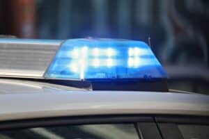 Ein E-Scooter, ein verletzter Mann und Polizeiauto im nächtlichen Stadtbild von Hennef.