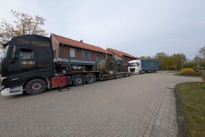 Überladener Sattelzug mit Polizei, Warnschilder und Kontrollstelle auf Autobahn; Sicherheitsüberprüfung im Fokus.