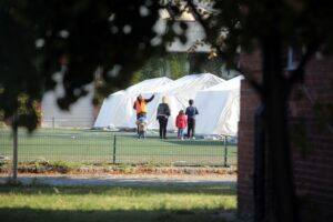 Flüchtlingsfamilie in einer Zeltstadt, symbolisiert erhöhte Abschiebungen und EU-Migrationspolitik.