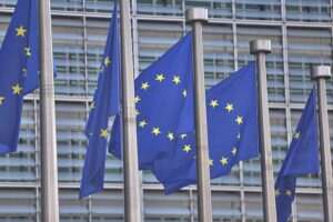 EU-Fahnen im Hintergrund, symbolisieren Sanktionen gegen Russland und Unterstützung für die Ukraine.
