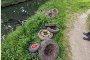 Illegal entsorgte Altreifen am Flussufer, Gefahr für Wasserqualität, Polizei sucht Zeugen.