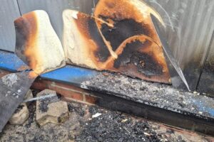 Feuerwehrmann untersucht Fassade der Sporthalle, während Einsatzkräfte aufgrund Fehlalarm abbestellt werden.