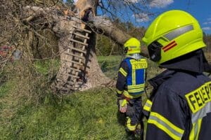 Feuerwehr löschen Brand an Hochsitz und Wohngebäude; Einsatzkräfte vor Einsatzfahrzeugen.