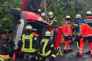 Rettungseinsatz: Feuerwehr befreit eingeklemmte Frau aus umgekippetem PKW auf Parkplatz.