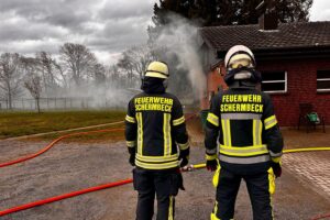 Einsatzkräfte der Feuerwehr löschen einen Zimmerbrand in Schermbeck, starke Rauchentwicklung sichtbar.