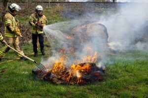 Feuerwehr löscht brennende Rundballen auf Streuobstwiese; Einsatzkräfte bei der Brandbekämpfung.