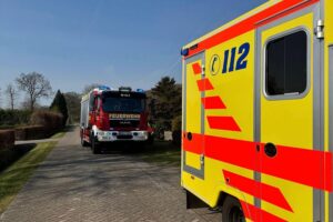 Feuerwehrleute öffnen Tür und helfen bei Transport einer hilfsbedürftigen Patientin ins Krankenhaus.