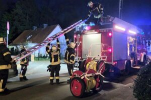 Feuerwehr löscht Küchenbrand in verrauchter Wohnung; Rettungsdienst versorgt verletzte Person.