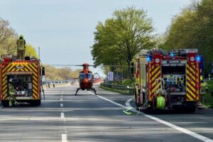 Zwei beschädigte Autos auf Autobahn, Rettungskräfte versorgen fünf verletzte Personen, Unfallstelle abgesichert.