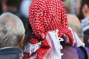Mann mit Kufiya, Symbol für den Konflikt, vor historischer Gedenkstätte als Protest.