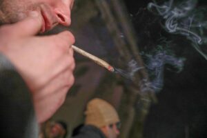 Cannabis-Demonstration vor dem Brandenburger Tor, Menschen mit Plakaten und Rauch.