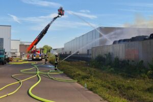 Löscharbeiten durch Feuerwehr mit Drehleitern und Wasserwerfern, zahlreiche Einsatzkräfte im Einsatz.