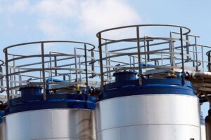 Öltanks und Container, die symbolisch für steigende Rüstungs kosten im Verteidigungsbereich stehen.