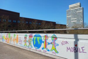 Graffiti von Kindern und Jugendlichen verschönern Fußgängerbrücke in Kaiserslautern, fördern Kreativität.