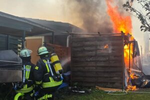 Große Rauchentwicklung und brennende Lauben in einer Kleingartenkolonie, Feuerwehr im Einsatz.