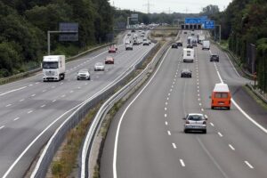 Pendler auf Autobahn, Benzinpreise steigen, Diskussion um Pendlerpauschale und soziale Ungleichheiten.