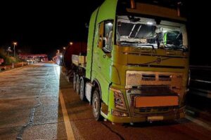 Überladener Schwertransporter mit Kabeltrommel und Stahlseil auf Raststätte, Polizei kontrolliert Transport.