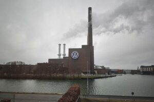 Volkswagen-Logo mit Autos im Hintergrund, symbolisiert Marktveränderungen und Exportstrategie.