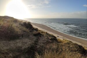 Sonniger Strand mit Dünen, ideal für milde Temperaturen und ruhiges Hochdruckwetter.