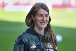 Hier sehen wir Marie-Louise Eta als erste Cheftrainerin im Fußball, umgeben von Stadionstimmung.