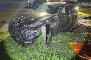 Rettungshubschrauber im Einsatz, Unfallstelle mit beschädigtem Auto und Zaun, Polizei vor Ort.