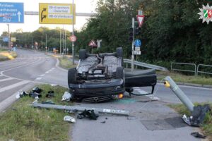 Schwerer Verkehrsunfall: Überschlagtes Auto, beschädigte Ampelanlage, Polizei und Rettungskräfte vor Ort.