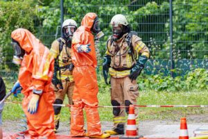 Feuerwehrkräfte in Schutzkleidung bei Ammoniakaustritt am Krankenhaus, Einsatz nach Leckagen.