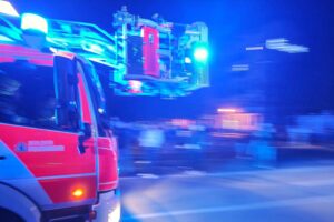 Rettungskräfte im Einsatz, Feuerwehr vor verrauchtem Wohnhaus, Einsatz nach Küchenunfall.