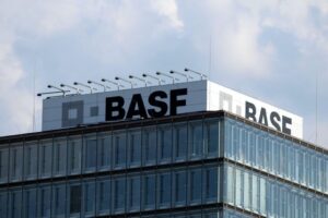 Logo von BASF, Darstellung von Sparmaßnahmen, Busy-Büros und motivierte Mitarbeiter im Hintergrund.
