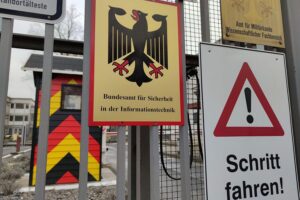 Symbolische Darstellung von Cybersicherheit: Computer, Schutzschilde, vernetzte Daten, alarmierende Warnsymbole.