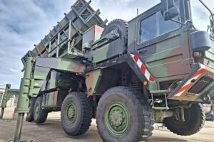 Patriot-Raketensystem mit Soldaten in militärischer Umgebung, Symbol für Nato-Luftverteidigung und Zusammenarbeit.