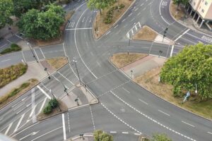 Komplexe Straßenkreuzung mit Verkehrsschildern und Fahrern, symbolisiert Verkehrssicherheit und Unfallvermeidung.