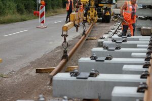 Baustelle einer Bahnlinie: Arbeiter, Schienenwechsel, Baugeräte, gesperrte Gleise und Ersatzbusse.