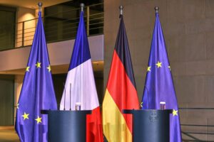 Fahnen von Frankreich, Deutschland und EU, symbolisieren Zusammenarbeit in nuklearer Abschreckung.